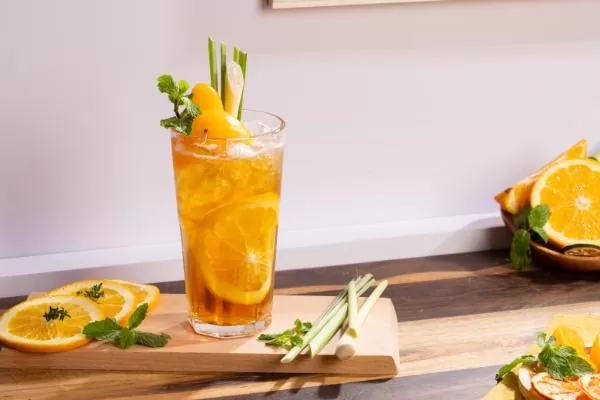 Cách pha chế: Bước 1: Cam vàng mua về bạn rửa sạch rồi cắt đôi quả cam, một nửa cắt múi cau, nửa còn lại vắt lấy nước cốt. Sả cắt gốc, bỏ phần vỏ già héo bên ngoài và lá. Cắt sả làm 2 hoặc 3 phần theo chiều dọc rồi đập dập cho vào nồi đun lấy nước, để lại 1 cây trang trí. Nước đun sôi đổ vào cốc rồi cho 2 túi trà vào ngâm trong khoảng 3 phút. Bước 2: Cho nước cốt sả, nước cốt cam, nước trà, đá viên vào bình lắc rồi lắc đều tay cho đến khi thân bình lạnh thì ngưng, việc lắc bình sẽ tạo nên một lớp bọt mỏng đẹp mắt. Sau đó cho thêm syrup đào và syrup cam vào ly trà cho vị đậm đà hơn. Bước 3: Sau khi nếm vừa miệng, bạn cho thêm đào ngâm vào, cam cắt lát, 1 cây sả rồi thưởng thức. Vậy là hoàn thành món trà đào cam sả thơm ngon, bạn có thể dùng một cọng sả thay thế cho đồ khuấy sẽ là điểm nhấn, khiến người thưởng thức thêm thích thú với món thức uống tuyệt vời này của bạn. Ngoài trà đào cam sả, bạn có thể làm trà đào chanh sả để thỉnh thoảng đổi vị cho trà đào sả.