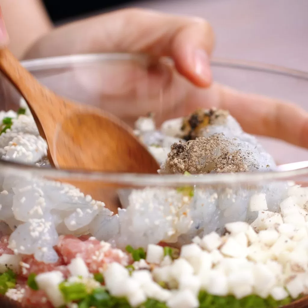 Cách làm há cảo hấp nhân tôm thịt: Bước 1: Sơ chế nguyên liệu: – Thịt heo rửa sạch, để ráo nước rồi băm nhuyễn. Không nên xay kỹ quá, thịt nát quá sẽ ảnh hưởng đến vị ngon của há cảo. – Tôm tươi rửa sạch, bóc vỏ, bỏ đầu, rút hết phần chỉ đen ở sống lưng, bóc vỏ, băm nhỏ thịt tôm. – Nấm mèo ngâm với nước cho nở, cắt chân, rửa sạch rồi băm nhuyễn. – Hành tím bóc vỏ, đập dập, băm nhuyễn. Hành lá nhặt gốc, rửa sạch, thái thật nhỏ. Cà rốt gọt vỏ, rửa sạch, xắt hạt lựu nhỏ hoặc băm nhỏ. Bước 2: Trộn bột làm vỏ bánh: – Bột năng và bột gạo trộn chung vào một tô lớn. Lấy khoảng 200ml nước sôi có muối vào một tô khác, khuấy đều đến khi muối tan, nước nguội bớt thì đổ từ từ vào tô bột. – Dùng đũa khuấy đều nước với bột rồi dùng tay nhào bột thành một khối mịn, dẻo và không dính tay. Ủ bột trong vòng 5 phút. Bước 3: Trộn nhân bánh: – Cho tất cả nguyên liệu bao gồm thịt heo, tôm, cà rốt, nấm mèo, hành tím, hành lá vào một cái tô, thêm gia vị rồi trộn đều tất cả. Nêm nếm gia vị sao cho vừa ăn. Tùy vào khẩu vị mỗi gia đình mà nêm nếm khác nhau và nguyên liệu chuẩn bị cũng khác nhau Bước 4: Cách làm há cảo phần vỏ bánh: – Sau khi ủ, bột mềm và mịn hơn, bạn dùng tay vê bột thành những đoạn dài, tròn rồi cắt bột thành những miếng dày. Tiếp đó, dùng cây cán bột hoặc chai thủy tinh sạch cán cho miếng bột thật mỏng, hình tròn, độ dài vừa phải, vỏ bánh mỏng quá hoặc dày quá cũng không nên. – Khi cán bột, bạn đậy kín những phần bột chưa làm bằng màng bọc ni lông vì nếu để lâu trong không khí bột sẽ bị khô. Tránh các côn trùng đậu vào gây mất vệ sinh Bước 5: Cho nhân vào vỏ há cảo: – Lấy lượng nhân vừa đủ cho vào giữa miếng bột, dùng tay nhúng chút nước bôi quanh mép của miếng bột rồi gấp đôi lại, bóp nhẹ để hai mép của miếng bột dính nhau. Dùng ngón trỏ và ngón cái bóp nhẹ từng mép bánh và xếp chồng lên nhau cho đẹp. Làm lần lượt cho đến khi hết nguyên liệu. – Nếu bạn không được khéo tay, thì bạn có thể sử dụng khuôn làm bánh được bán trên thị trường để tạo hình trong đẹp mắt hơn Bước 6: Hấp há cảo: – Phết một lớp dầu ăn mỏng lên xửng hấp bánh để chống dính, sau đó lần lượt xếp bánh vào. Đun nước sôi, cho bánh vào hấp trong vòng 10 – 15 phút (tùy kích thước bánh to nhỏ) đến khi vỏ bánh trong là được. Lấy bánh ra ngoài và thưởng thức. – Làm nước chấm: Băm ½ củ tỏi nhỏ và ½ trái ớt, cho vào chén cùng 2 muỗng nước mắm ngon rồi khuấy đều. Cho thêm 3 muỗng nước sôi để nguội và ½ muỗng đường vào khuấy cho đến khi tan đường. Cuối cùng, vắt thêm chút nước cốt chanh, khuấy đều. Có thể thay đổi các gia vị cho phù hợp với khẩu vị của gia đình.